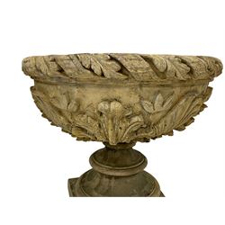 Pair of composite stone garden urn planters, acanthus leaf garland rim over foliate decorated body, stepped foot on square base