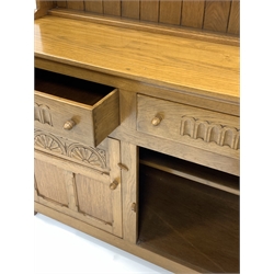 20th century light oak dresser, two height plate rack carved with Yorkshire rose roundels over two drawers and two panelled cupboard doors enclosing shelf, raised on stile supports, W122cm, H169cm, D46cm