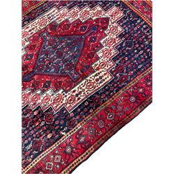 Persian indigo ground rug, the central crimson geometric medallion banded by repeating lozenges, the field decorated profusely with interlacing geometric motifs, the guarded border with stylised plant patterns