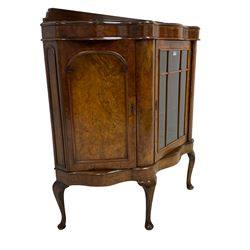 Early 20th century figured walnut serpentine side cabinet, shaped top with raised back, fitted with centre astragal glazed door enclosing two glass shelves, flanked by two arch panelled cupboards, raised on cabriole supports with pad feet