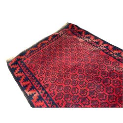 Persian Baluchi crimson ground runner rug, the field with all-over dark indigo geometric patterns, enclosed by borders of Vitruvian waves and repeating geometric shapes