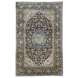Persian Kashan indigo ground carpet, the central floral medallion surrounded by all-over foliate motifs and palmettes, the dark indigo field with pale contrasting spandrels, the multi-band border with repeating interlaced palmettes and branches