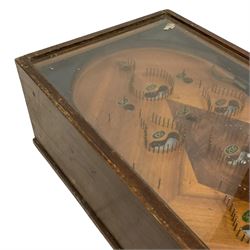 Early 20th century table top bagatelle game 'Uneda', in oak case with glazed top and coin operated mechanism, figured inlaid mahogany surface with painted scores