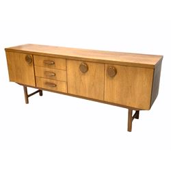 Mid 20th century teak sideboard, fitted with three drawers and a fall front cupboard to centre, flanked by two further cupboards, raised on square supports.