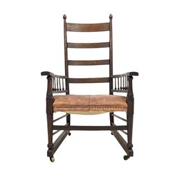 Possibly William Birch for Liberty - Early 20th century arts and crafts period stained beech open armchair, the high ladder back over arms supported by spindle gallery and seat upholstered in studded leather, raised on turned supports with floor stretchers terminating in castors W61cm