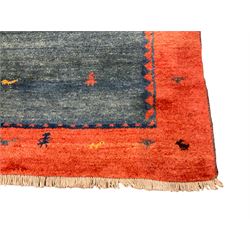 Persian Gabbeh indigo ground thick pile carpet, the field and thick red border decorated with stylised animal and camel motifs, with weaver figures around the guard stripe, retailed by Fired Earth