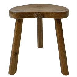 Mouseman - oak three-legged stool, figured dished kidney shaped top carved with mouse signature, on octagonal tapered supports, by Robert Thompson of Kilburn 