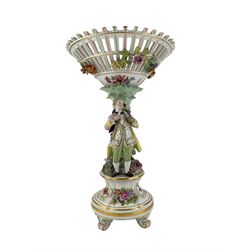 Continental porcelain centrepiece, the pierced basket form bowl painted and encrusted with flowers, the naturalistic stem modelled with a male and female figures, each in 18th century dress and picking flowers, the circular relief moulded base on four scroll supports, H45cm