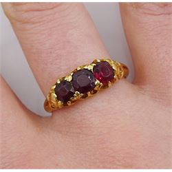 Early 20th century 18ct gold three stone garnet ring with scroll design shoulders