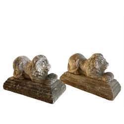 Pair of cast stone garden figures in the form of recumbent lions holding balls between their paws, raised on stepped moulded plinth bases, in crackled paint finish 