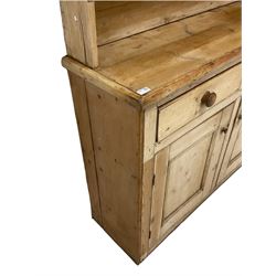 Rustic pine dresser, projecting cornice over two plate racks, the lower section fitted with two drawers and two panelled cupboards with wooden handles