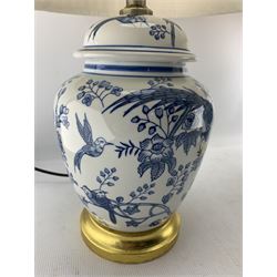 Pair of Chinese porcelain blue and white lamps in the form of ginger jars and covers, each decorated with exotic birds perched in flowering trees, raised upon gilt circular base, H58cm including shade