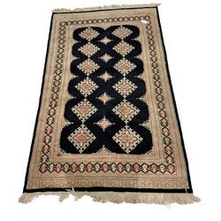 Persian design ground rug, black field with repeating lozenge medallions enclosed by multi lined boarder. 126 x 203cm.