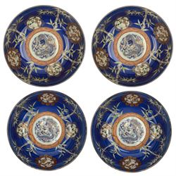Set of four Japanese graduating porcelain bowls, each centrally painted with a coiled dragon in reserves, bamboo and foliate roundels against a blue ground, largest measuring D24.5cm (4)