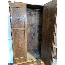 Early 20th century oak single wardrobe, with bevelled oval mirror enclosing interior fitted for hanging, one drawer under, raised on compressed bun supports