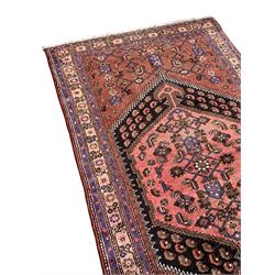 Persian Shiraz rose ground rug, the large hexagonal medallion containing and surrounded by Herati motifs with stylised bird symbols and flower heads, the guarded border with repeating trailing floral designs