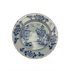 Two18th century Delft chargers and plate, one charger centrally painted with a landscape scene with rockwork, trees and birds D35cm, the other painted with Chinoiserie style flowers, and the plate, possibly Liverpool, painted in the chinoiserie style with floral sprays (3)