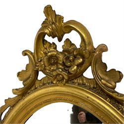 19th century giltwood and gesso wall mirror, moulded oval frame with scrolled cartouche pediment decorated with flower heads and trailing foliage, the outer frame with shell moulding, C-scroll and foliage lower decoration 