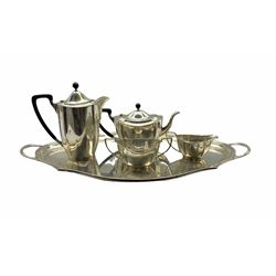 Silver four piece tea set of panel sided design, the tea pot and hot water jug with ebonised handles and lifts together with the matching two handled tray of oval design with serpentine border L69cm overall Birmingham 1936/7 Maker Barker Bros. Silver Ltd. approx 155oz