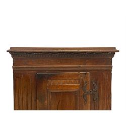 18th century carved oak standing cupboard, moulded projecting cornice over carved dentil decoration, the single panelled door with moulded slip decorated with **, the uprights carved with vertical arcade decoration and foliate design, with wrought metal fittings and handle, raised on bun feet