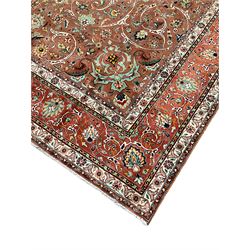 Persian carpet, rust ground field decorated with sweeping scrolls and stylised plant motifs, large floral design central medallion, repeating scrolling border with stylised flower head motifs 