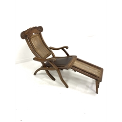 Early 20th century teak folding steamer chair, leaf scroll carved cresting rail, cane back and foot panel, and leather upholstered seat, W60cm