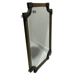 Brass framed wall mirror with rounded edges surrounding bevelled edge mirror