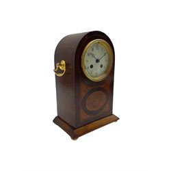 A decorative early 20th century French mantle clock in a round topped mahogany case with inlaid satinwood stringing and a contrasting oval and fan inlay to the front, white enamel dial with finely painted Arabic numerals and minute track,  matching steel moon hands within a decorative cast bezel and convex glass, eight-day French going barrel movement striking the hours and half hours on a coiled gong. With pendulum. 



