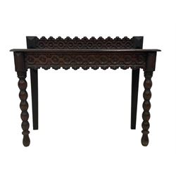 Late 19th century gothic revival oak side table the raised back carved with repeating rosette and fleur-de-lis motifs, the rectangular top with moulded edge, the apron with matching decoration, raised on bobbin turned supports 