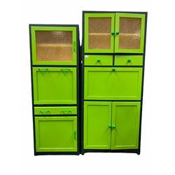 Vintage green painted kitchen cabinet, two glazed doors enclosing shelf over two drawers, a fall front cupboard and double cupboard to base, raised on stile supports (W77cm, H180cm, D40cm) together with another similar cabinet (W59cm, h164cm, D40cm)