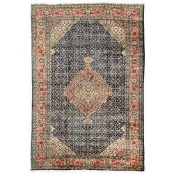 Persian pale indigo and peach ground rug, shaped central medallion within a field of repeating Herati motifs, the guarded border decorated with repeating stylised plant motifs