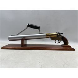 Early 20th century Schermuly line throwing pistol, walnut grip, brass body stamped SPRA and numbered 8704 and steel barrel, mounted on pine display stand, L50cm 
