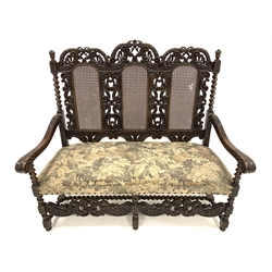 Early 20th century William and Mary style walnut hall seat, with cane panels to back, profusely carved with floral scrolls and foliate, upholstered seat, raised on spiral turned supports and stretchers