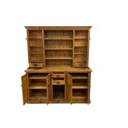 20th century pine dresser, projecting cornice over three central plate racks flanked by two cupboards and drawers, the lower section fitted with two drawers and two double cupboards with panelled doors, raised on plinth base