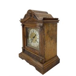 German - 8-day walnut cased mantle clock c1900, with a carved scroll pediment and reeded columns on a stepped plinth with a shaped base, square brass dial with a matted centre, steel hands cast spandrels and silvered chapter ring, twin train movement striking the quarters and hours on two coiled gongs. With pendulum. movement stamped 