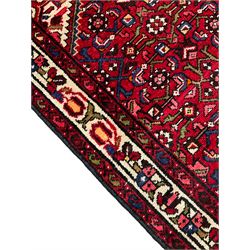 Persian Hamadan runner, red ground field with central stepped lozenge, decorated with larger Herati motifs, ivory band border decorated with geometric patterns