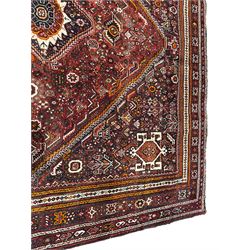 Persian Qashqai red ground rug, the extended lozenge field decorated with a central pole medallion comprised of three connecting diamonds, surrounded by all-over flower heads and stylised plant motifs, the multi-band border with repeating geometric shapes and Boteh motifs