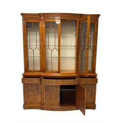 Yew wood shaped break-front display cabinet, the top section with projecting cornice over figured frieze, enclosed by four astragal glazed doors, with glass shelves, the lower section fitted with three drawers, double cupboard and two single cupboards, on plinth base