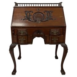 Late 19th century mahogany bureau, the raised back carved with gadroon decoration and supported by brass spindles, the fall-front decorated with central moulded shell and extending foliate applique concealing fitted interior, lower section fitted with central frieze drawer over two shorted drawers, the moulded apron carved with gadroons, the cabriole supports with moulded foliate knees terminating in ball and claw feet