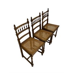 Set of six Edwardian oak dining chairs, the rail back with spindle gallery over cane seat panel, raised on turned and fluted front supports W45cm