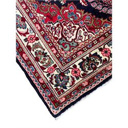 Persian Qom blue ground rug, the field decorated with central scrolling medallion surrounded by eight floral urns and stylised plant motifs, floral decorated spandrels and repeating guarded border