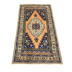 Persian ground rug, with central medallion of blues, greens, reds, and ivory, on an orange field, enclosed by multi line border
