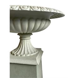 Pair of cast iron two-piece garden urns on plinths, egg and dart moulded rim over gadrooned underbelly, moulded footed base, on tapered square plinth
