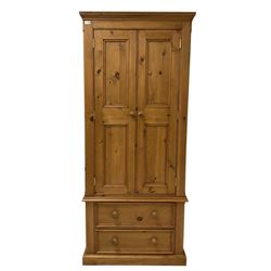 Waxed pine double wardrobe, fitted with two doors, opening to reveal interior fitted for hanging over two drawers, raised on a plinth base