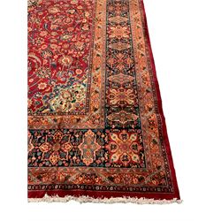 Persian crimson ground carpet, pale floral design central medallion and spandrels, the field decorated with swirling branches interspersed with stylised plant and leaf motifs, signature panel to end, the border decorated with repeating panels and smaller floral motifs, the guard stripes with trailing foliage pattern
