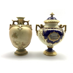  Royal Worcester 2-handled baluster vase decorated with lake landscapes in gilt on a blush ivory ground, date code for 1900 H19cm and a Coalport lidded vase painted with a small landscape panel on a dark blue, gilt and cream ground H20cm  