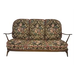 Mid-20th century medium elm ercol three seat sofa, the spindle back with loose patterned cushions of foliate design, raised on turned supports 