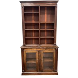 Early Victorian mahogany library bookcase on cupboard, projecting cornice over applied floral roundels and egg and dart beading, fitted with eight open shelves, two glazed doors each enclosing a shelf under, raised on skirted base W118cm, H230cm, D40cm