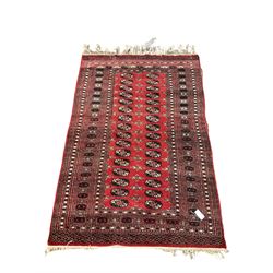 Afghan Bokhara red ground rug, with repeating gul motif, enclosed by multi band border
