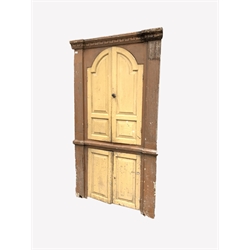  Early 19th century pine corner cupboard, dentil cornice over two arched panelled doors enclosed by fluted pilasters, two panelled doors under, W114cm  